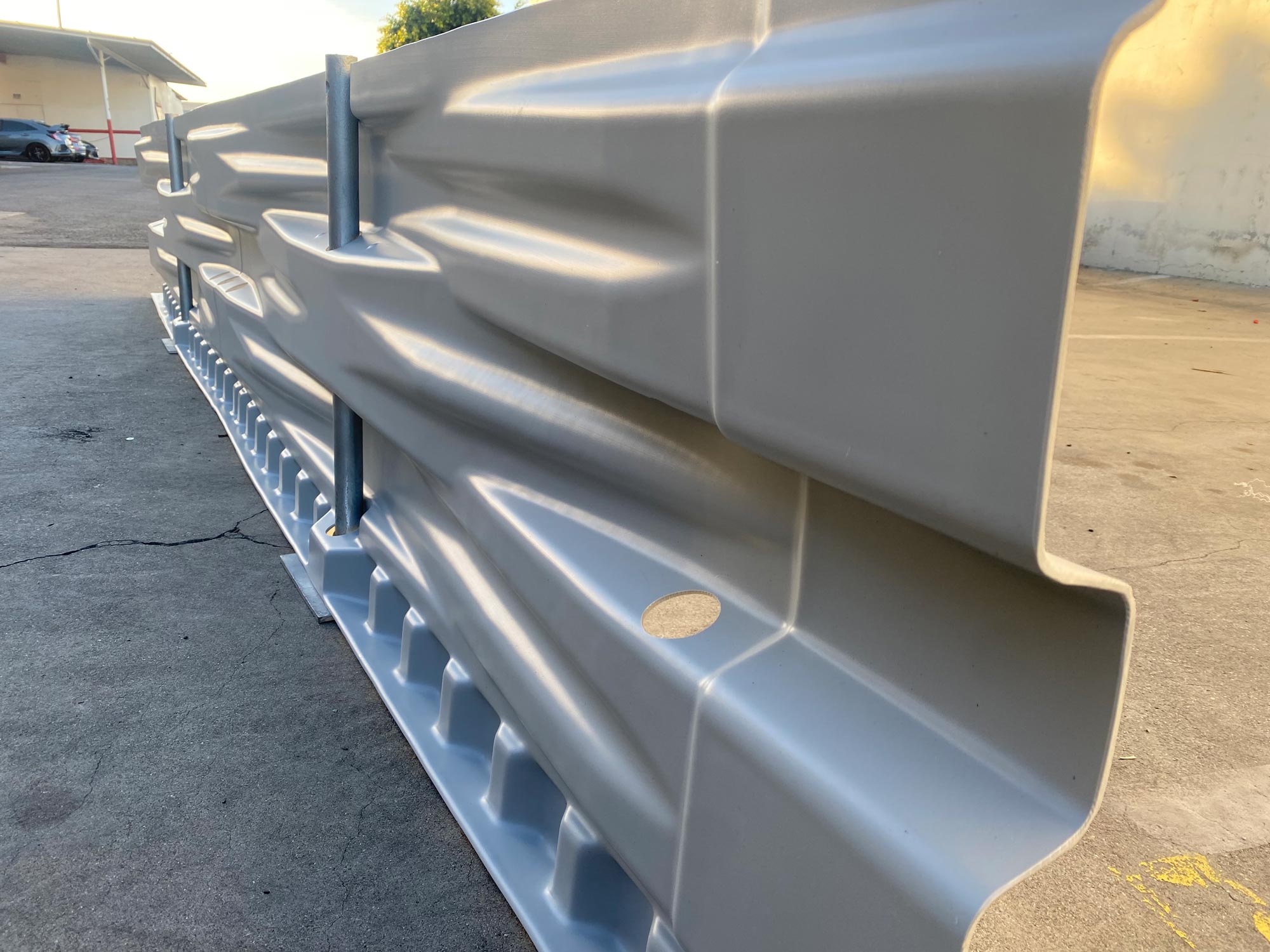 Close-up view of a metal road safety barrier installed on a concrete surface in an outdoor area.