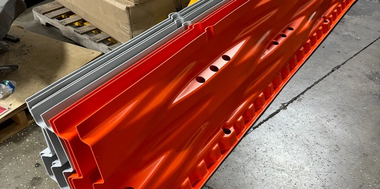 Several stacked orange and gray plastic safety barriers sit on a warehouse floor near cardboard boxes.