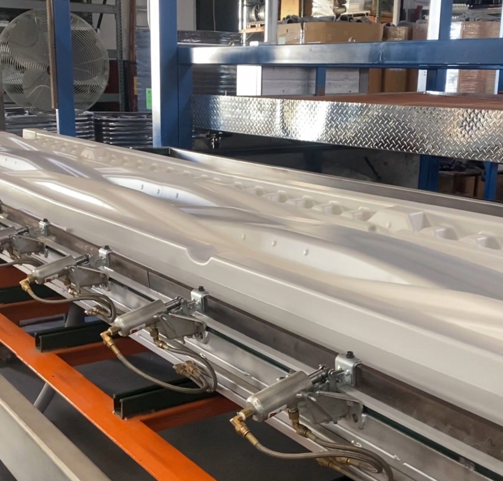 White industrial equipment with metal pipes and nozzles inside a factory setting.