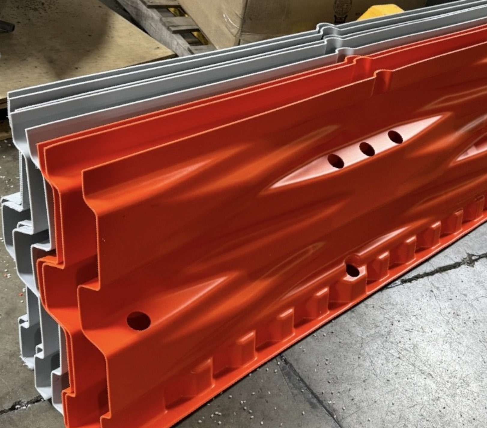 Stacked orange and gray plastic safety barriers on a warehouse floor.
